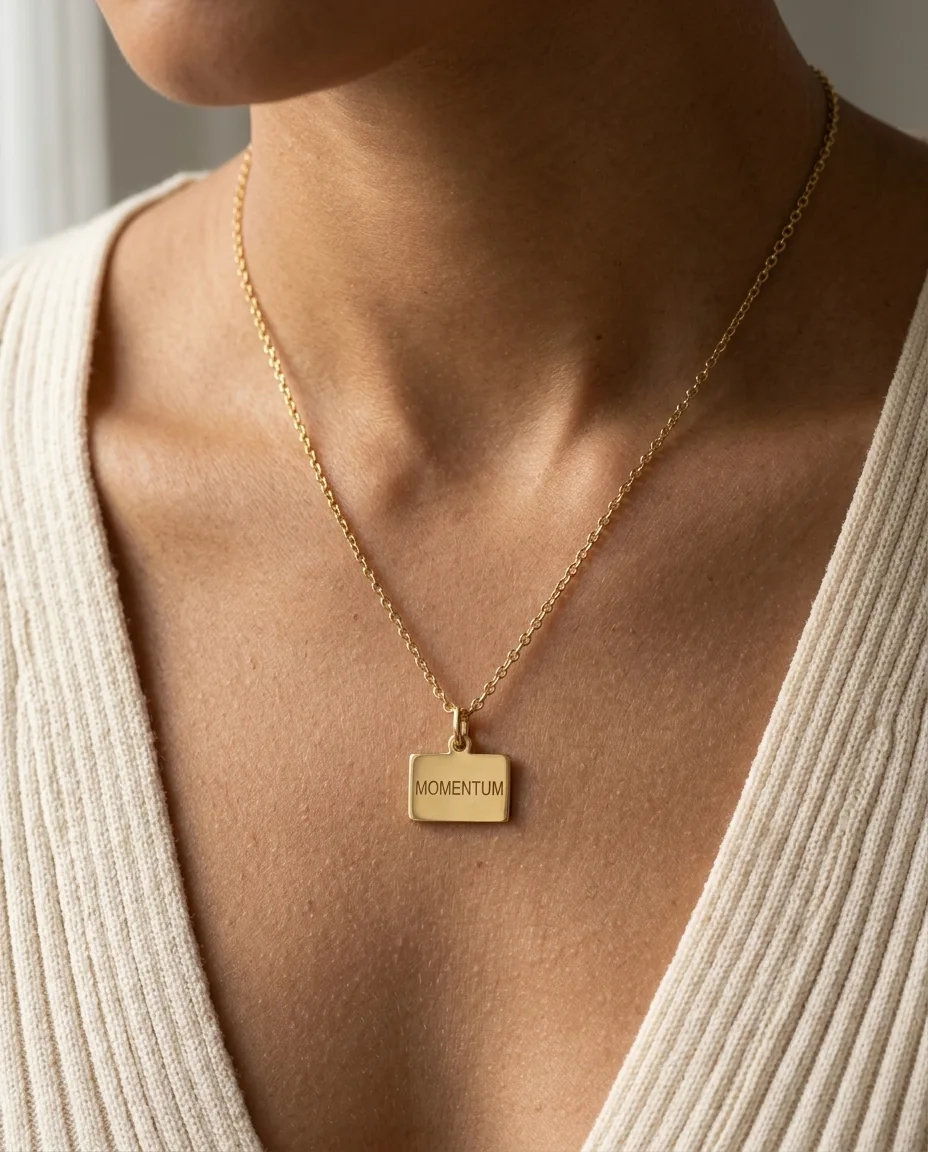 A gold pendant necklace worn on the neck