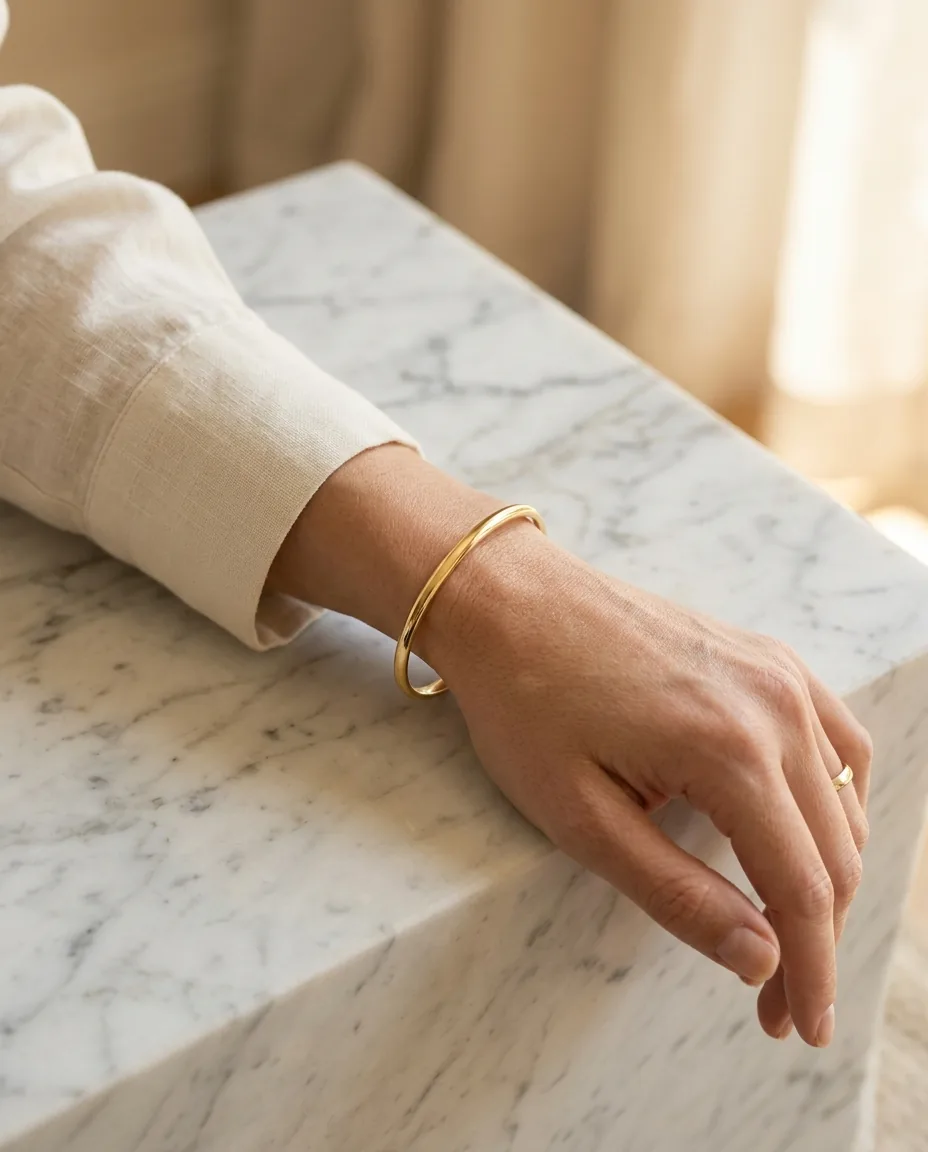 A gold bangle worn on a wrist